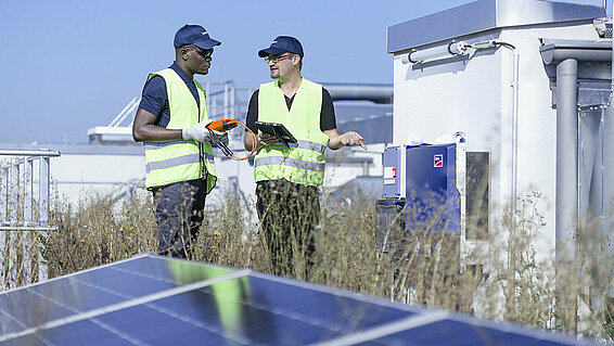 Two Leadec employees on factory roof with photovoltaic panels.