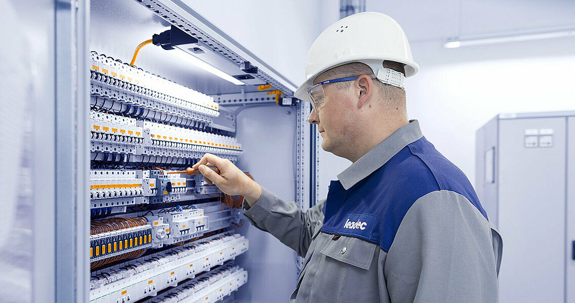 A Leadec employee working at a control cabinet.
