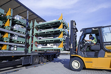 A Leadec employee uses a forklift to load pallets of batteries onto a truck.