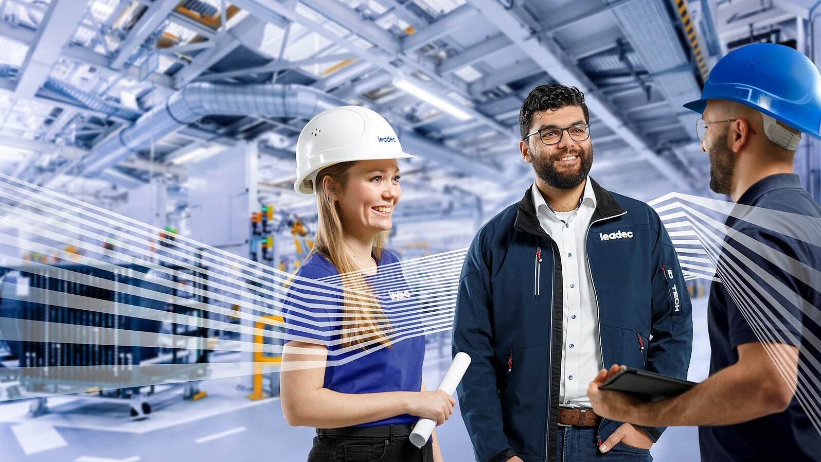 Three Leadec employees in workwear talking in front of a factory background.